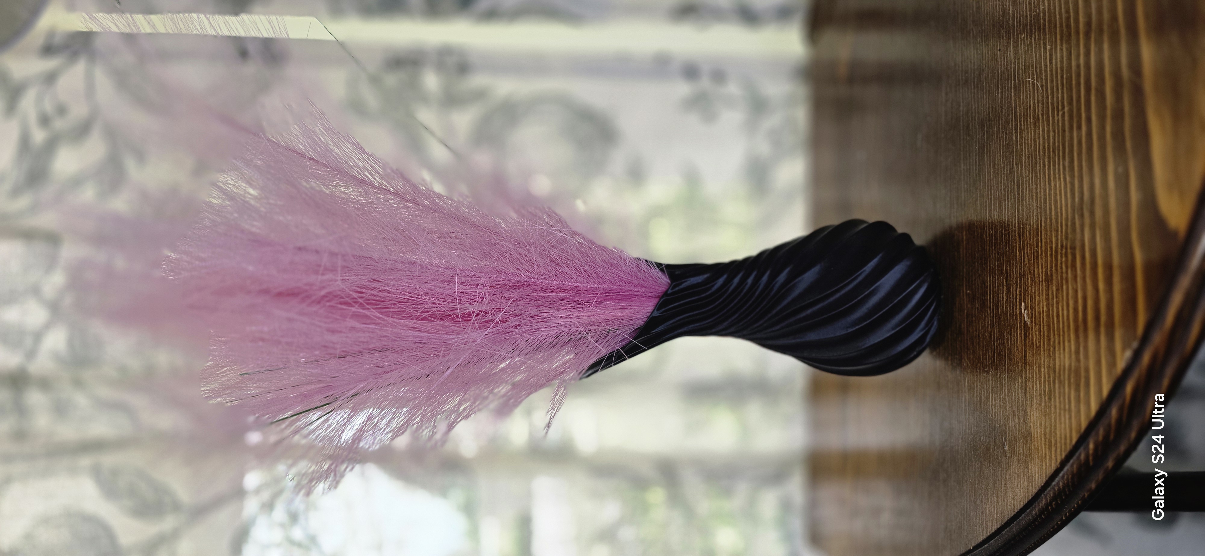 Black twisted 3D-printed vase with pink pampas grass on a wood table